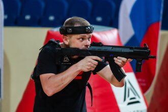Игрок LASERWAR с автоматом у красного укрытия в полной готовности.